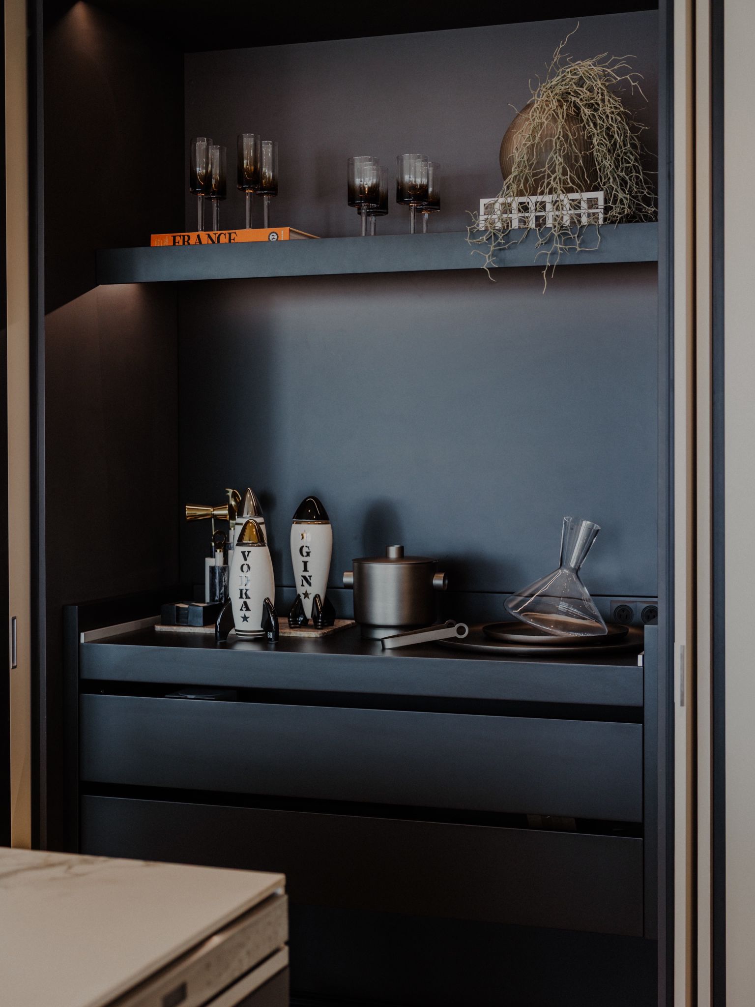 Charcoal travertine bar with amber bottles.